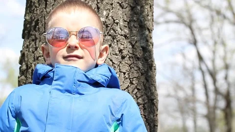 Boy in stylish glasses in forest is smiling and waving on the camera Stock Footage 106808087