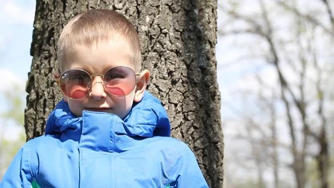 Boy in stylish glasses in forest is smiling and waving on the camera Video stock 106808110