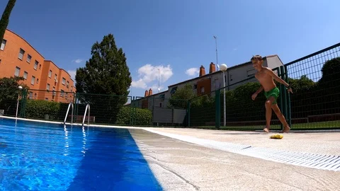 Boy in the summer on vacation jumping into the pool in the open air Stock Footage 111856611