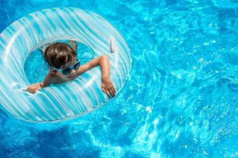 Boy in sunglasses swims in pool with float Stock Photos
