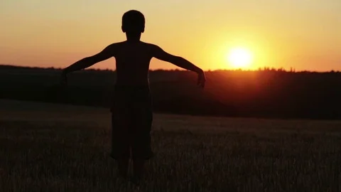 The boy at sunset does exercises running around the field. Stock Footage 77564549