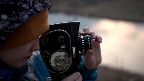 A boy at sunset on a high Bank takes a picture of the landscape Stock Footage 128330195