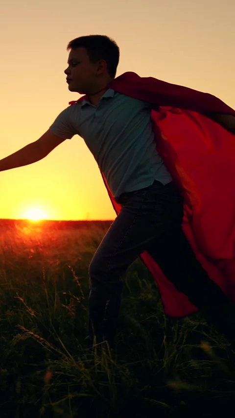 Boy in superhero costume pretends to be fantasy character flying across field Stock Footage 322195576