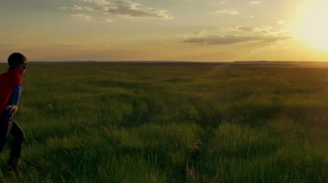 Boy superhero in a field at sunset Stock Footage 63990984