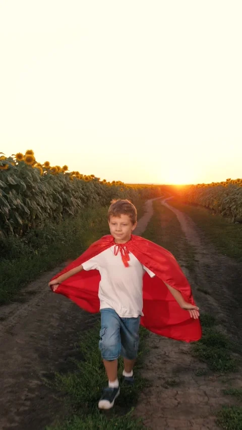 Boy superhero imagination, red cape countryside playtime, child hero sunset Stock Footage 282678234