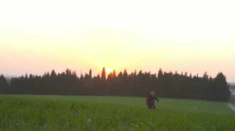 Boy with a Superman cape running in a field during sunset Stock Footage 59307925