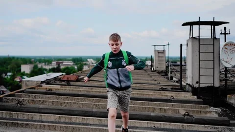 A boy in a sweater and a backpack on his back jumps Stock Footage 318071270