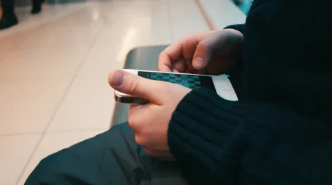 Boy in a Sweater is Playing in the Smartphone While His Parents Are Shopping at Stock Footage 61069460