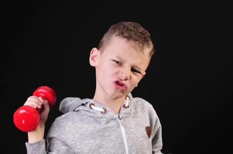 Boy in sweatshirt doing a workout with red dumbbells Stock Photos