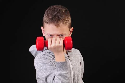 Boy in sweatshirt doing a workout with red dumbbells Foto stock