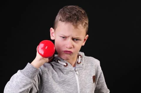 Boy in sweatshirt doing a workout with red dumbbells Stock Photos