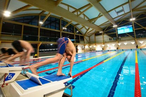 Boy swimmers start from the starting table in the pool Stock Photos
