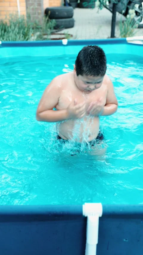 Boy swimming in backyard pool with blue water summer day outdoor activity brick Video stock 312548545