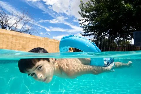 Boy swimming in pool with float ring Stock Photos