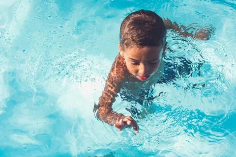 Boy swimming in pool with watermelon float Foto stock