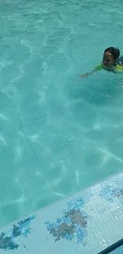 A boy is swimming in a swimming pool whose water is blue and clear Stock Photos