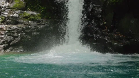 Boy swimming in turquoise natural pool at base of tropical waterfall. Stock Footage 338370751