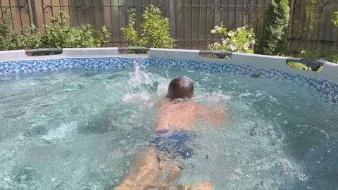 Boy Swims and Splashes in Backyard Pool Stock Footage 348089496
