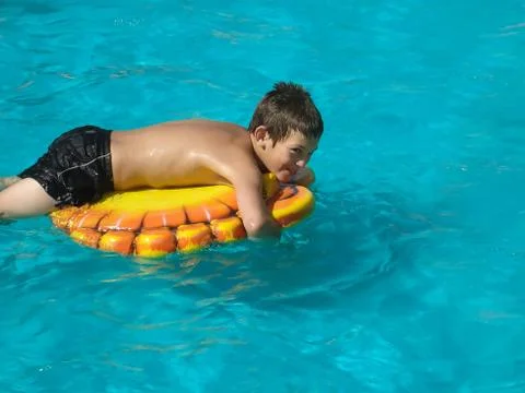 A boy swims in pool on a rubber ring Stock Photos