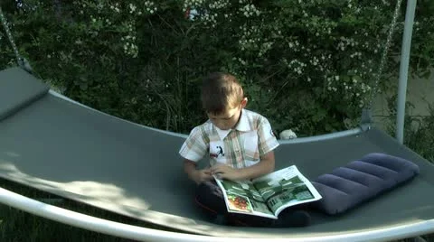 Boy on a swing with a magazine Stock Footage 11290118
