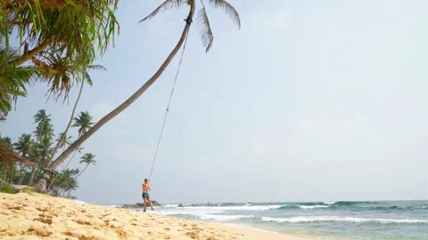Boy swinging on the palm tree on the white beach on Sri Lanka 스톡 동영상 168589767