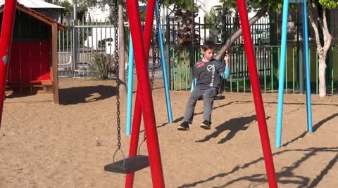 Boy swinging in playground Stock Footage 14869983