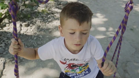 Boy swinging on a rope swing Stock Footage 94346982