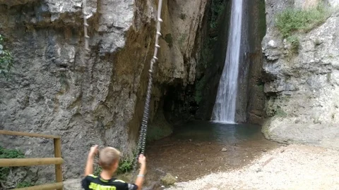 Boy swinging on a swing touching a waterfall in La Molina park, Verona - Italy Video stock 118160146