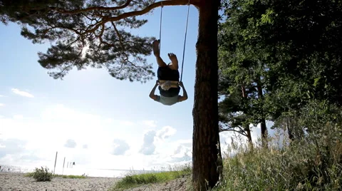 Boy swinging on a swing under a high pine tree Stock Footage 52963631
