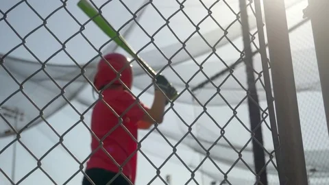 A boy swings the bat and practices little league baseball at the batting cages, Stock Footage