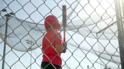 A boy swings the bat and practices little league baseball at the batting cages, Stock Footage