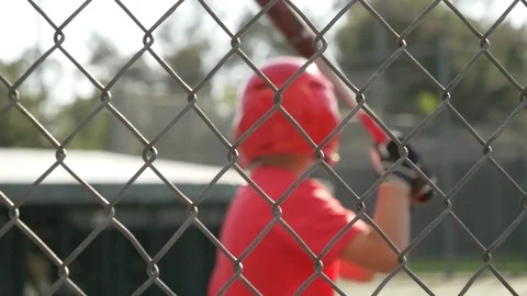 A boy swings the bat and practices little league baseball at the batting cages, Stock Footage