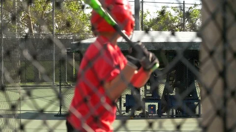 A boy swings the bat and practices little league baseball at the batting cages, Stock Footage