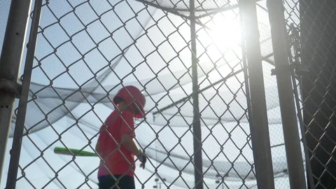 A boy swings the bat and practices little league baseball at the batting cages, Stock-Footage 80525834