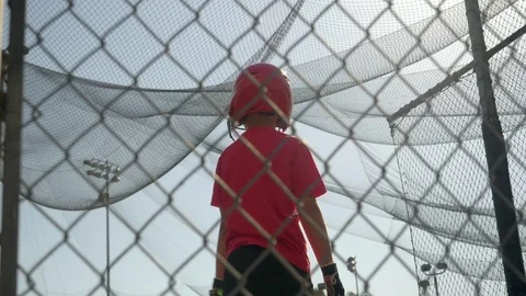 A boy swings the bat and practices little league baseball at the batting cages, Stock Footage