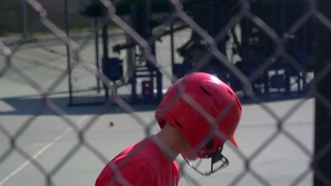 A boy swings the bat and practices little league baseball at the batting cages, Stock Footage