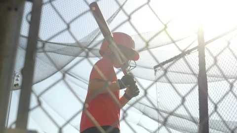 A boy swings the bat and practices little league baseball at the batting cages, Stock Footage
