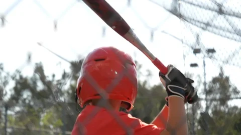 A boy swings the bat and practices little league baseball at the batting cages, Stock Footage 91744341