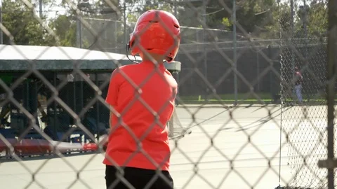 A boy swings the bat and practices little league baseball at the batting cages, Stock Footage 91744933