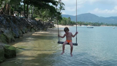 A boy swings overlooking the sea Stock Footage 78997831