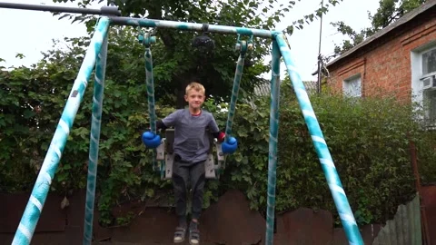 A boy swings on a swing in the backyard Vídeo Stock 207768080