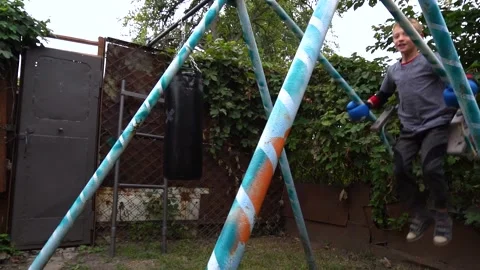 A boy swings on a swing in the backyard Stockbeeldmateriaal 207768469