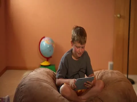 Boy With Tablet on Beanbag Stock Footage 12063746