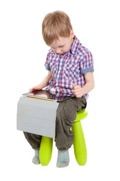 Boy with a tablet pc sitting on a chair Stock Photos