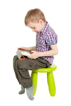 Boy with a tablet pc sitting on a green children's chair Stock Photos