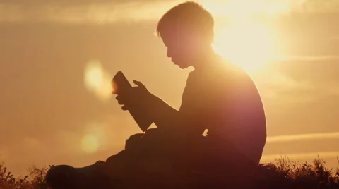 Boy with tablet at sunset sitting on the mountain Stock Footage