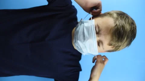 A boy take off a face mask on a blue background, vertical video Stock Footage 141532150