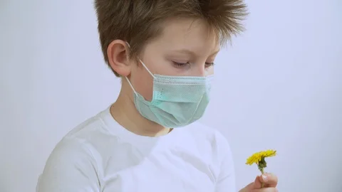 Boy take off the protective mask, breathe scent of yellow dandelion in his hand Stock Footage 127836050