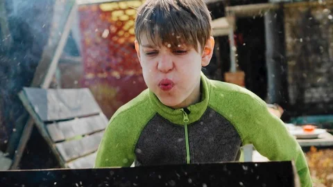 The boy takes a deep breath and blows hard on the coals in the grill Stock Footage 130049040