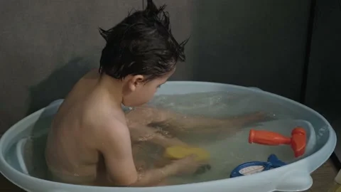 Boy taking a bath playing with yellow toy duck. Splashing water. Infant washing Stock Footage 190593321